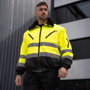 Mann trägt 4-in-1 Premium Pilotenjacke Oslo in Warnfarbe mit Leuchtstreifen, abnehmbarem Innenfutter und Ärmeln, wasserabweisend für Winter und Übergang.
