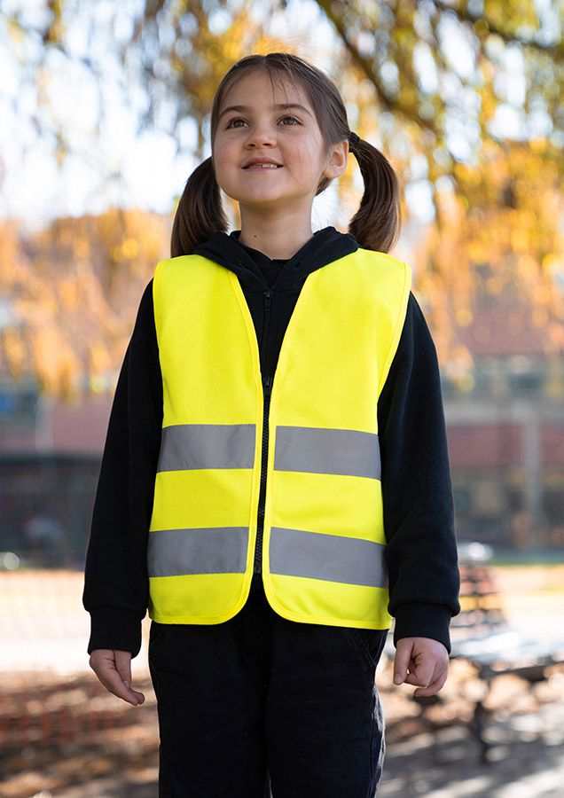 Kind wearing bright yellow Korntex Reißverschluss-Warnweste for children with reflective strips outdoors